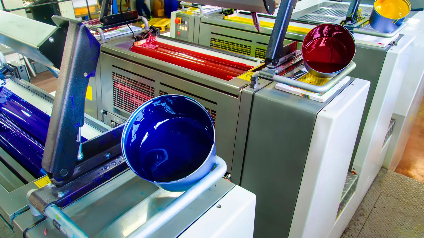Máquina de impresión offset con tinta azul y roja en los rodillos